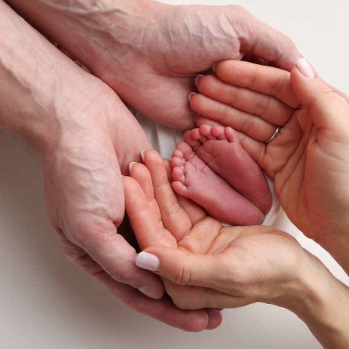 Two hands surround a babys feet